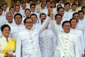 Cambodian opposition leader Sam Rainsy (C-L) raises hands with Kem Sokha (C-R), deputy of Cambodia National Rescue Party (CNRP) in front of members of parliament before the swearing in ceremony inside the Royal Palace in Phnom Penh on August 5, 2014. Rainsy and 54 other members of his party were sworn in as members of parliament on August 5, after a year-long boycott of parliament triggered by a disputed election. AFP PHOTO/ TANG CHHIN SOTHY / AFP PHOTO / TANG CHHIN SOTHY